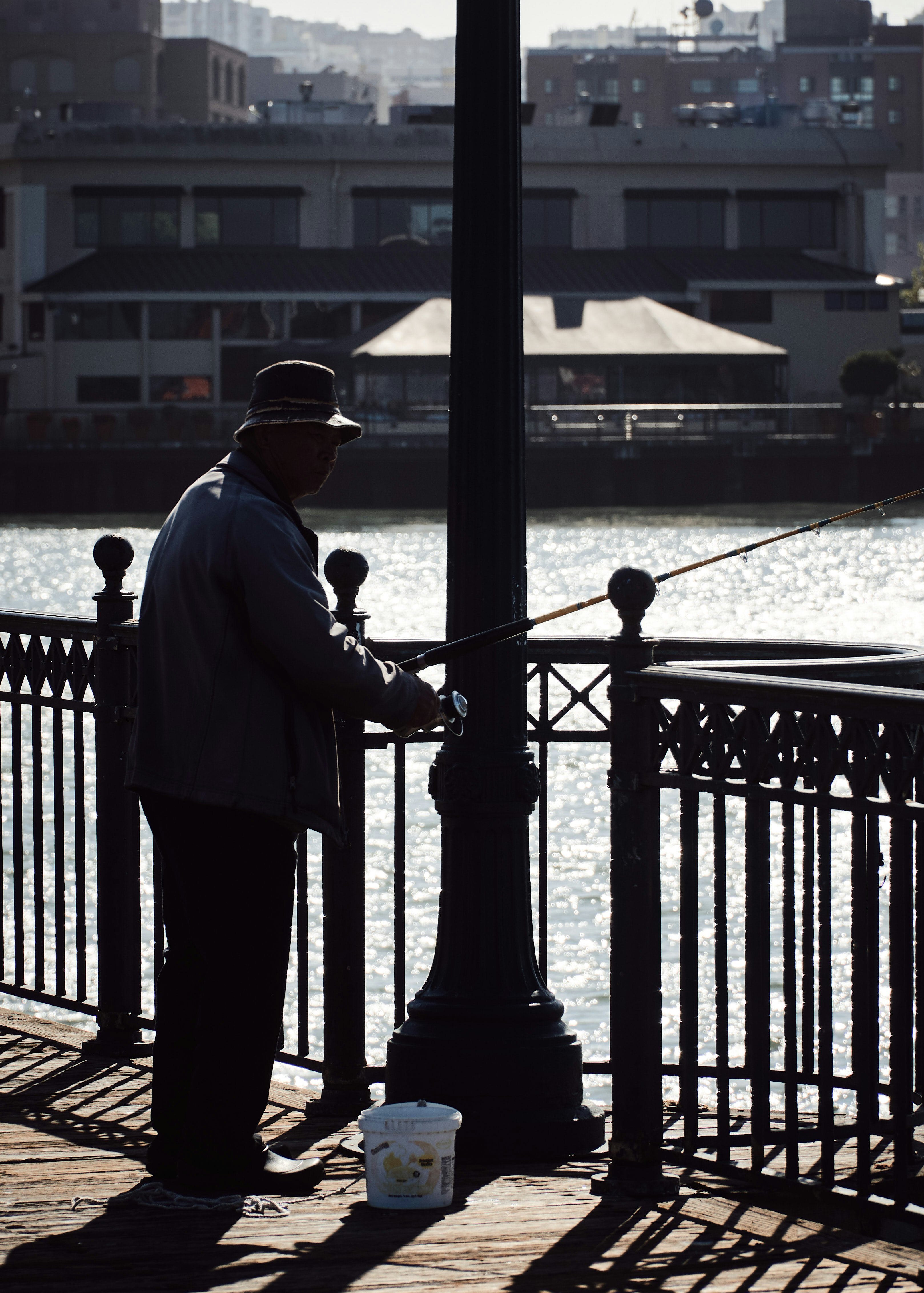 man holding fishing rod while standing near metal post